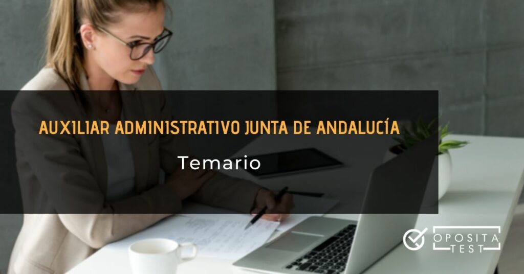 Mujer rubia de traje blanco ante ordenador portátil y papeles con printer para acompañar la temática temario de la oposición a auxiliar administrativo de la Junta de Andalucía